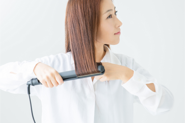 サラサラの髪にヘアアイロンを使用する女性